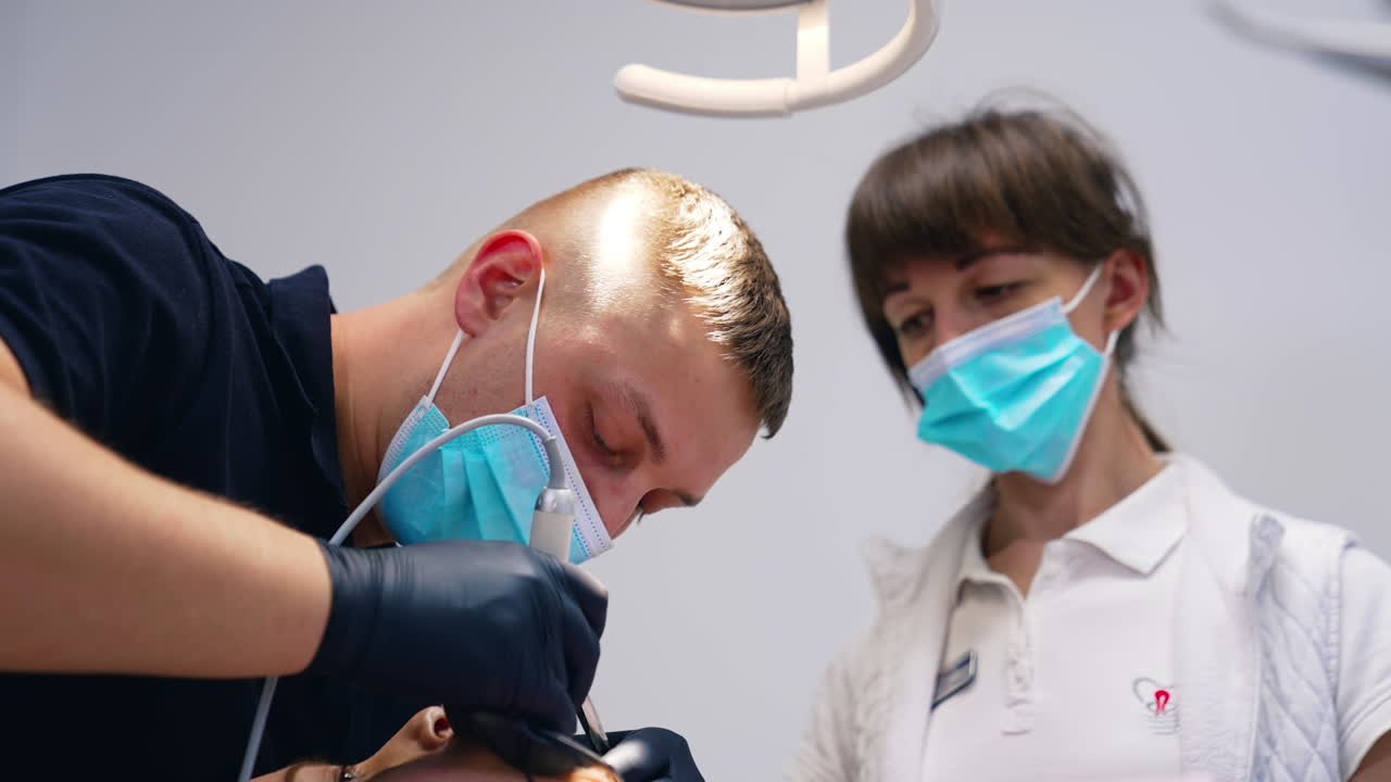 Coppia di medici stomatologi che lavorano sui denti di un paziente. Trattamento odontoiatrico dei denti.