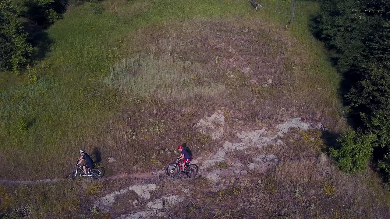 Riding On A Bike On Forest Path. Cyclist riding the bike on the trail near the forest and river
