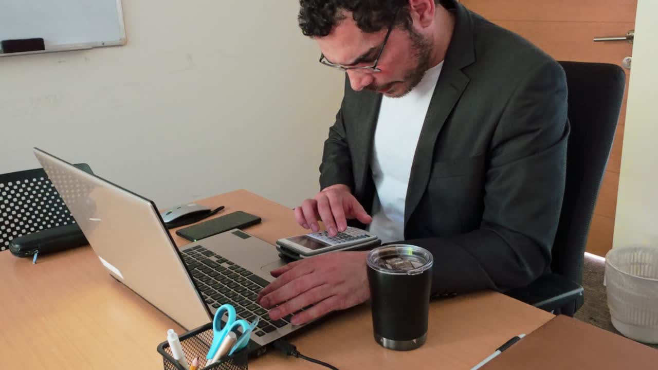 Young Man Crunching Numbers at Office Desk