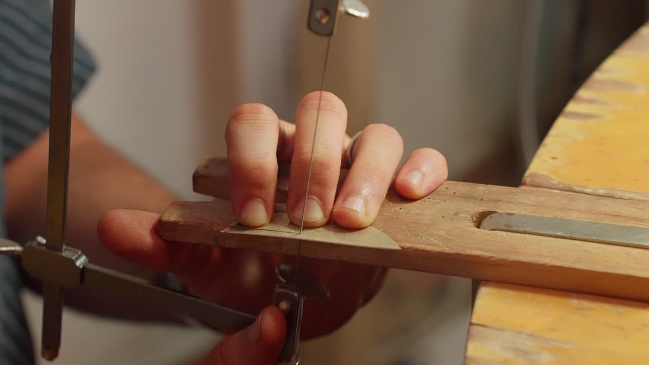 A person guides a saw along a piece of wood, with precision while working in a workshop filled with tools and materials, showcasing woodworking skills.