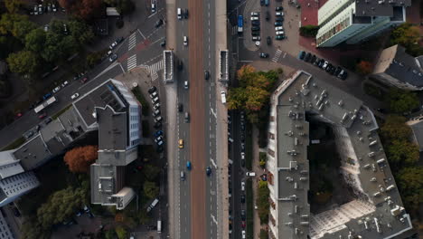 Aerial-birds-eye-overhead-top-down-panning-view-of-wide-street-with-tram-tracks.-Tracking-of-cars-driving-in-town.-Warsaw,-Poland