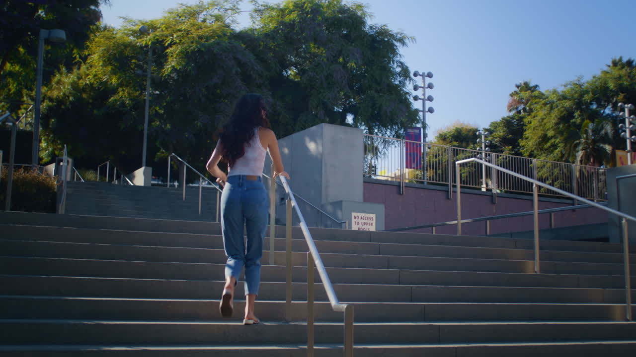 Cheerful brunette running upstairs. Asian girl ascend staircase to take picture.
