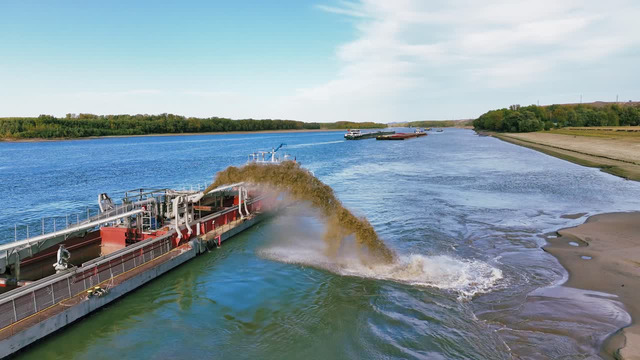 Aerial close up shot of a dredger unloading dredged sand on a big river, sunny day