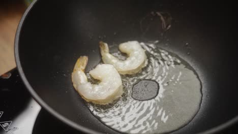 cocinero irreconocible fritando gambas en sartén con aceite caliente
