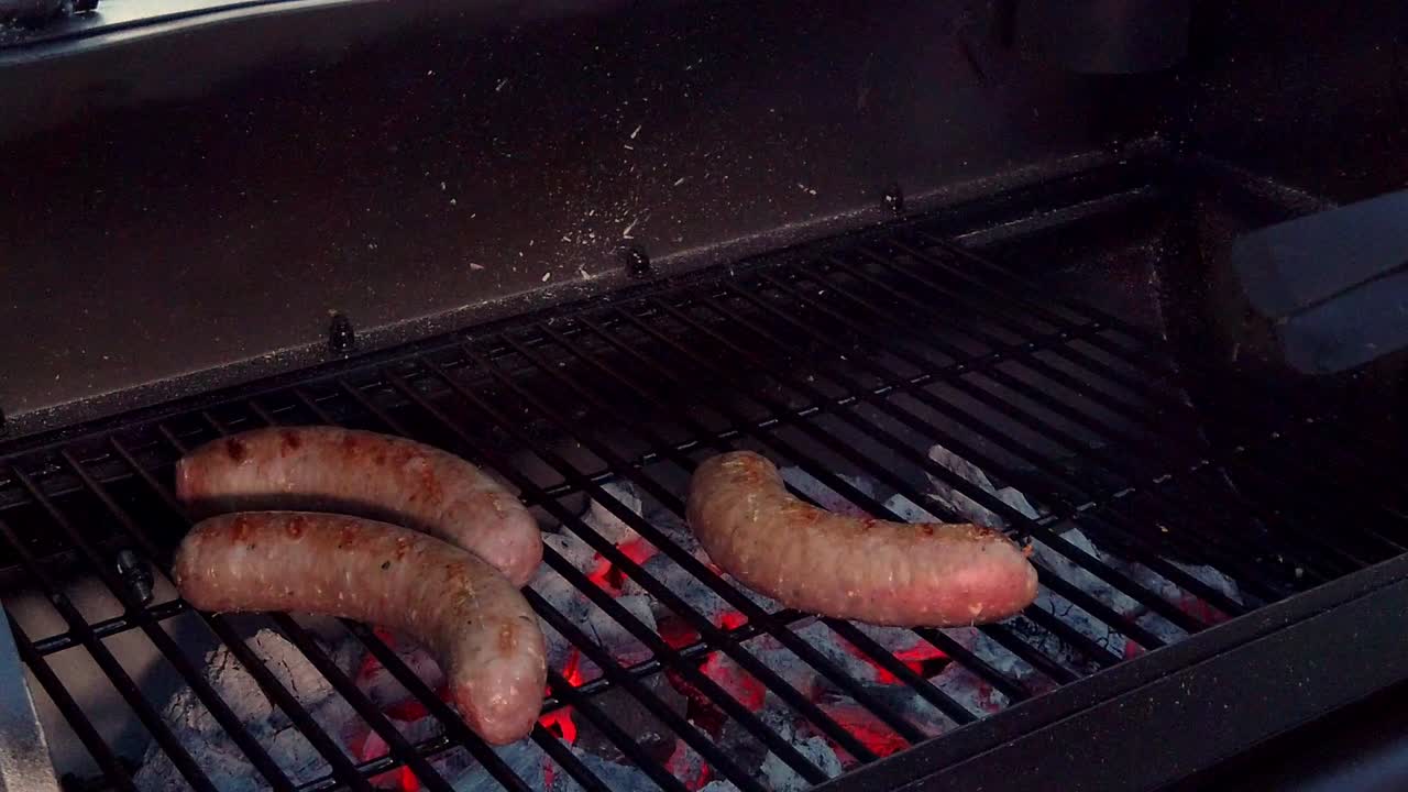 poner salchichas en la parrilla para cocinarlas en la barbacoa