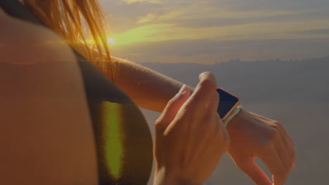 animación de luz brillante sobre mujer deportiva comprobando reloj inteligente por el mar