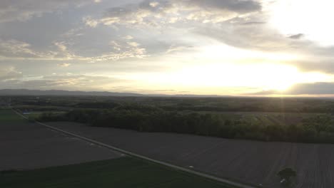 One-of-the-most-beautiful-shots-of-sunset-in-Bosnia-and-Herzegovina,-Brcko-district-flat-land-with-straight-roads-and-mountains-in-distance-with-green-trees-and-grass,-and-stunning-sunset