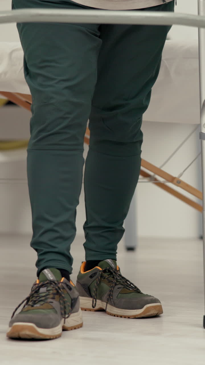Person's Legs and Feet Performing Rehabilitation Exercise with Walker