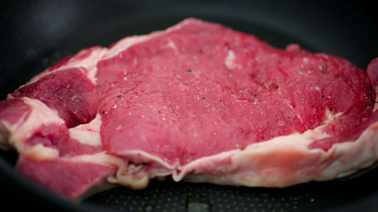 Close up of a rump steak cooking on a pan