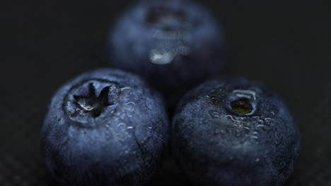 Close-up-macro-shot-of-blueberries-laying-on-dark-splashed-and-spayed-water-background-captured-water-drops-in-slow-motion