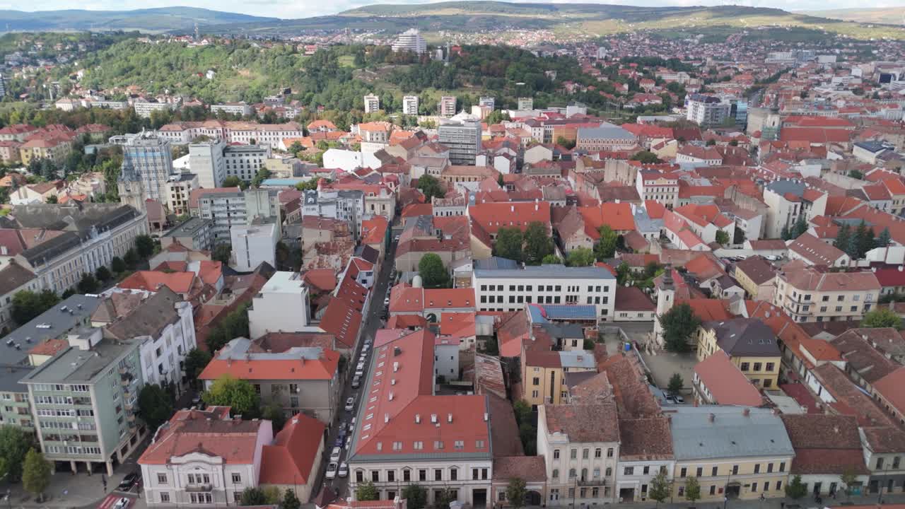 Red-roofed cityscape view with hills, shot at midday, vibrant atmosphere