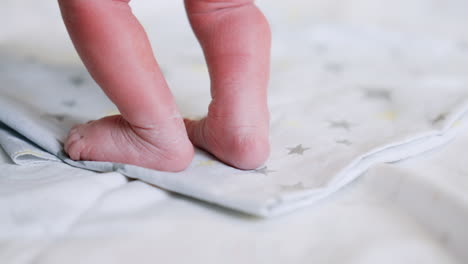 tiny naked newborn feet on the laid sheet. checking the child right after birth. close up.