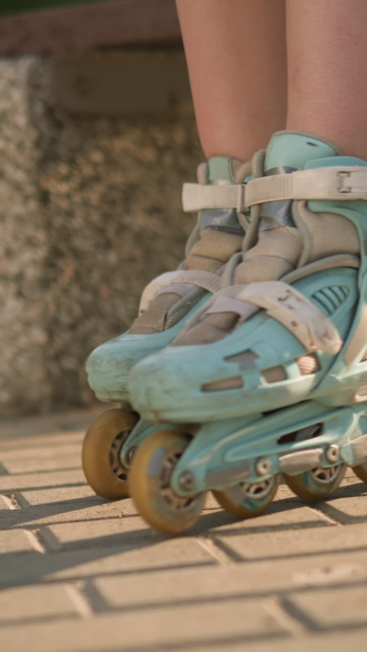 Leg view of lady in roller skates rolling back and forth on paved ground, sunlight casting shadows with sneakers slightly behind, with blurred background greenery and warm sunlight