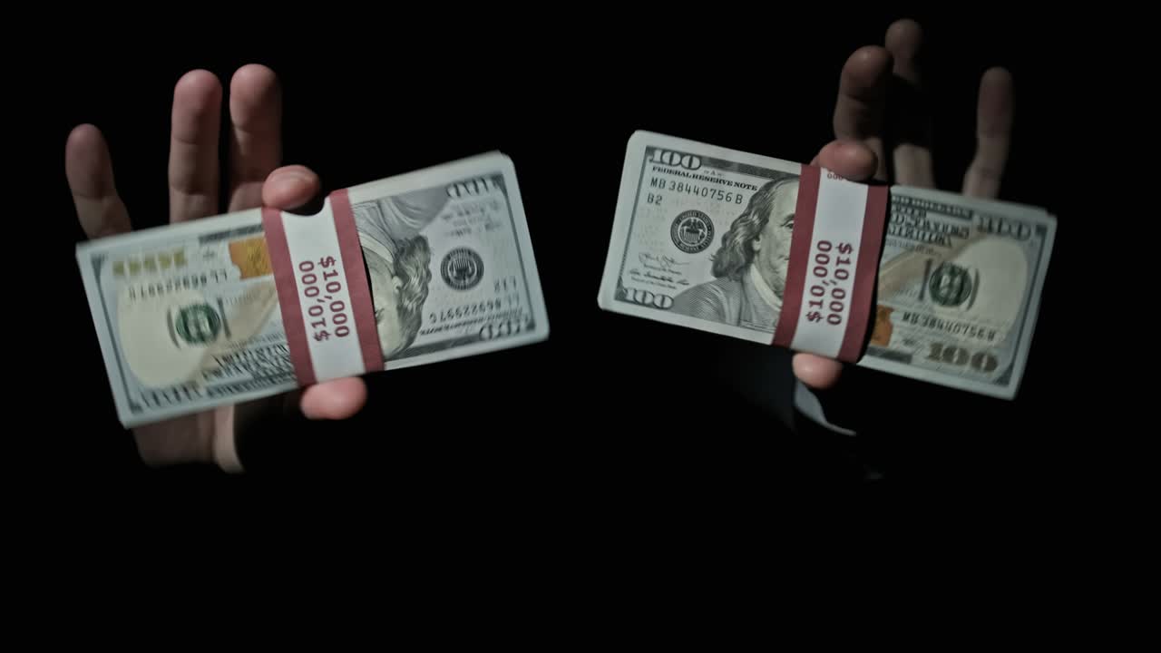 검은색 배경에 남성의 손에 10,000 미국 달러의 두 어리