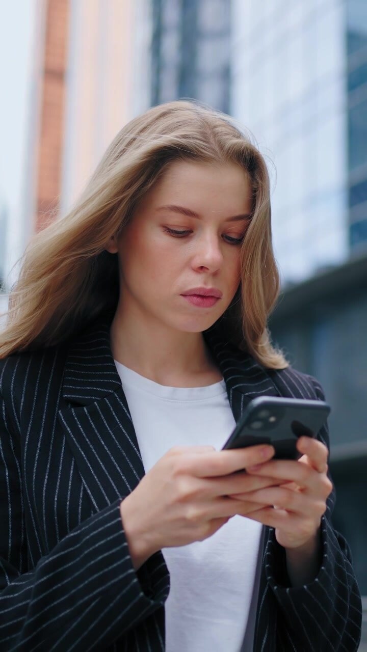 Young Businesswoman Using Smartphone Outside Modern Office Building