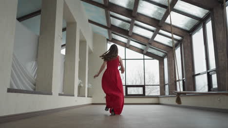 modelo en vestido ondulante se acerca rápidamente a la ventana. mujer joven crea un momento visualmente llamativo en movimiento en la galería de arte.