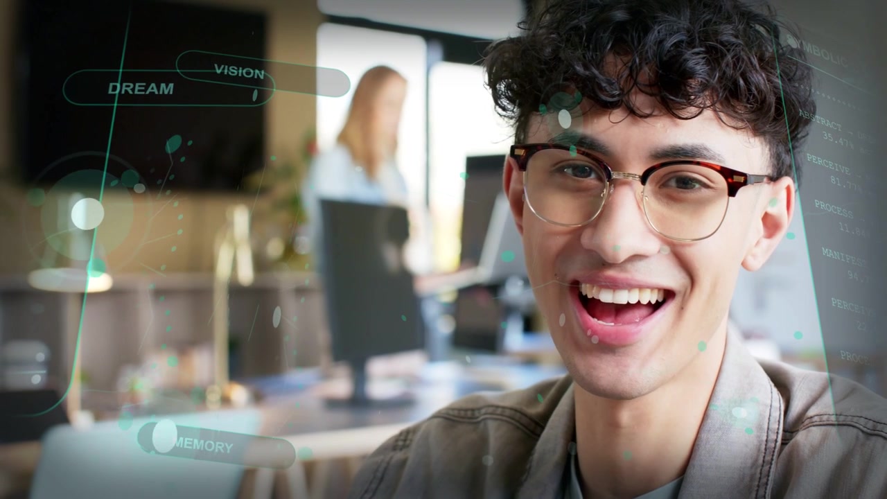 Uomo alla scrivania in un ufficio tecnologico che usa il laptop, reagendo all'apparizione di un HUD, spostando lo sguardo, sorridendo e ridendo.