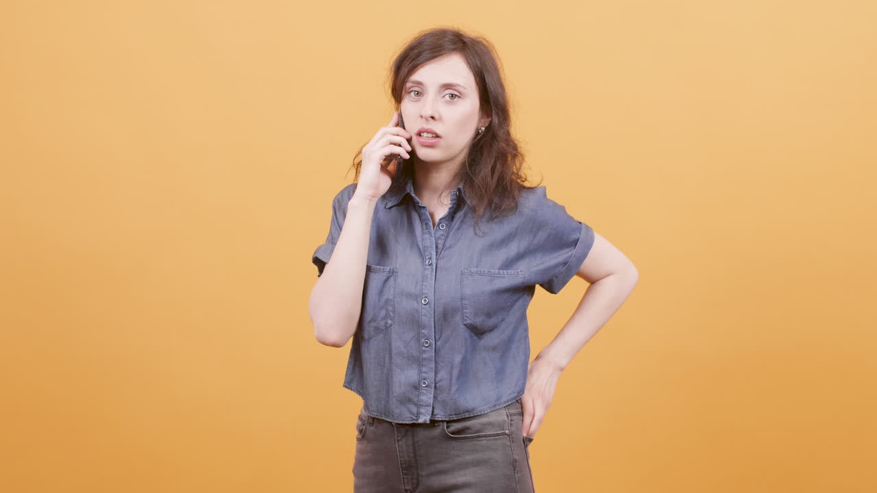 Woman talking on the phone in front of an orange background