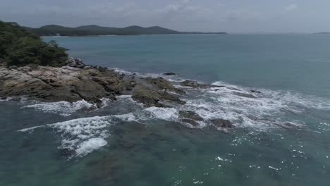 Vuelo-De-Drones-Sobre-Un-Afloramiento-Rocoso,-Un-Pequeño-Barco-De-Pesca-Y-El-Océano