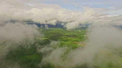 un paisaje verde cubierto de nubes con el mar en el fondo