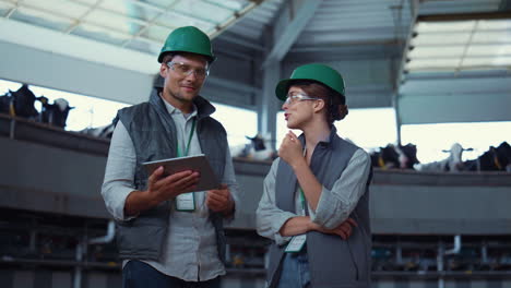 farm specialists talking dairy manufacture. supervisors holding pad computer.