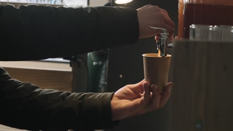 person pouring beverage from dispenser