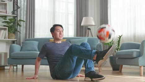 asian man sitting and show skill with soccer ball in living room, soccer freestyle