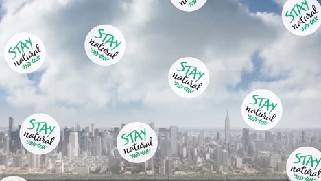 animation of circles with stay natural text moving over aerial view of cityscape against cloudy sky