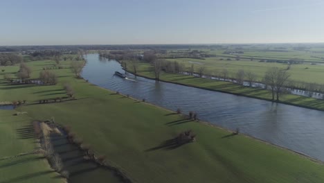 drone shot of a landscape with freighter boat going down the river