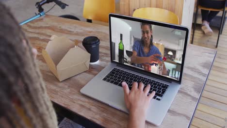 frau, die einen snack isst, während sie einen videoanruf auf dem laptop im café macht