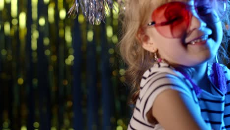 Hipster-cute-teenager-children-girl-looking-at-camera,-smiling-at-disco-party-club-in-neon-lighting