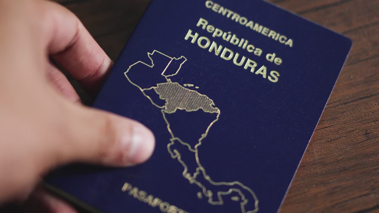la mano de un hombre pone el pasaporte de honduras en una mesa de madera durante la inspección rutinaria del aeropuerto