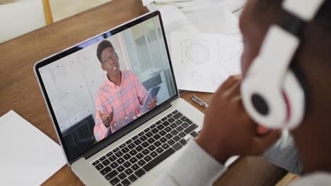 Estudiante-Universitario-Afroamericano-Sosteniendo-Notas-Mientras-Realiza-Una-Videollamada-En-Una-Computadora-Portátil-En-Casa