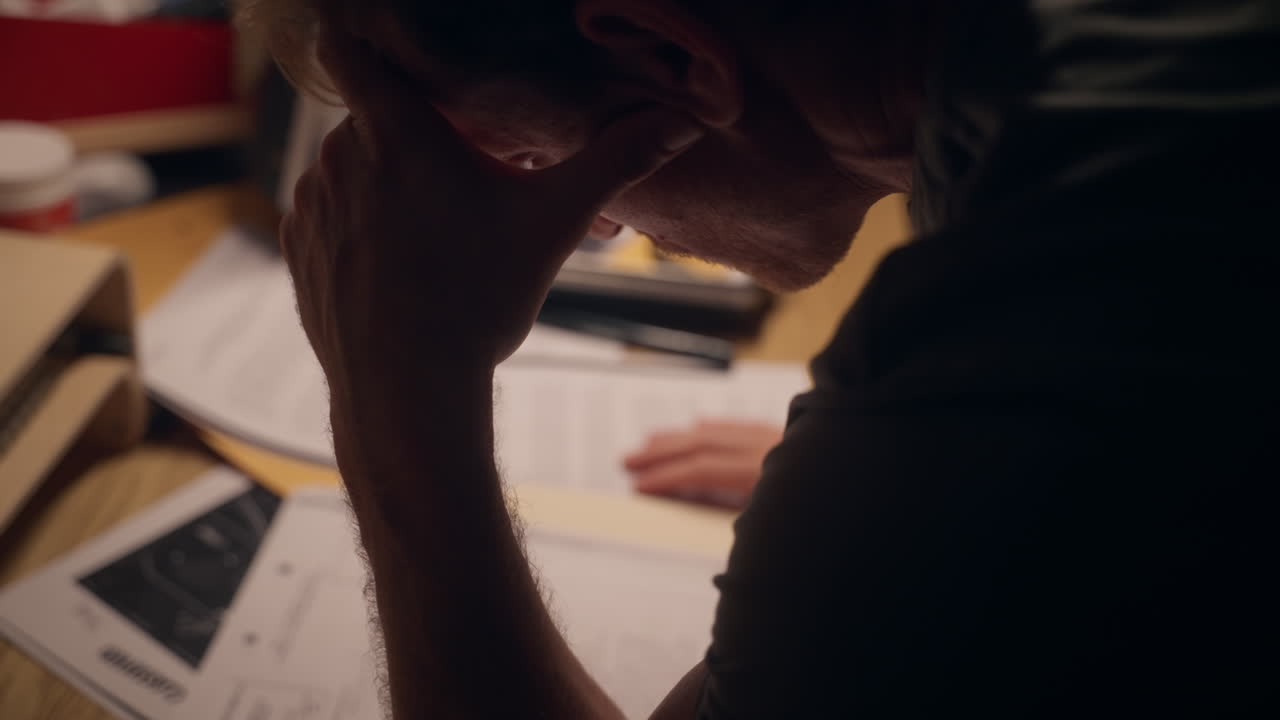 Man reading and looking at classified secret documents and reports on office desk. Agent spy or government mole or journalist reporter investigating and analyzing confidential sensitive text and info