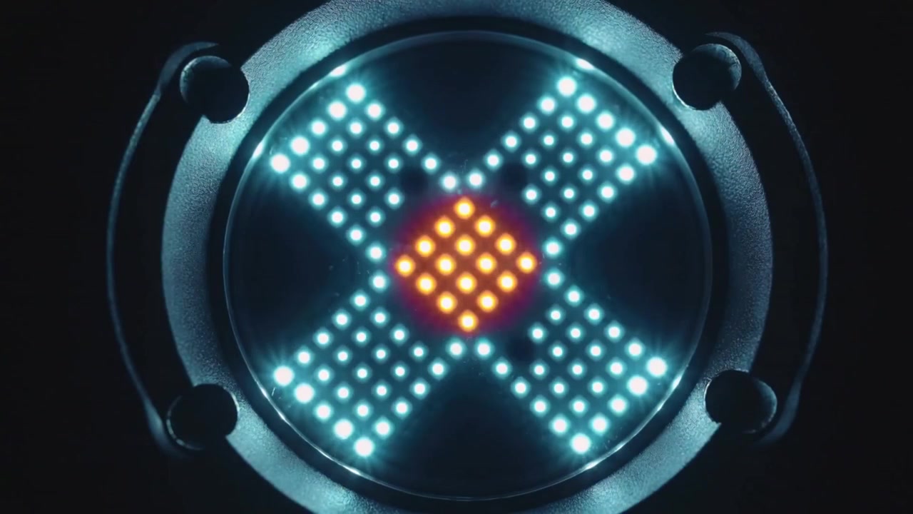 Powering on circular LED module showing cyan X and orange diamond in metal housing, magenta blinks