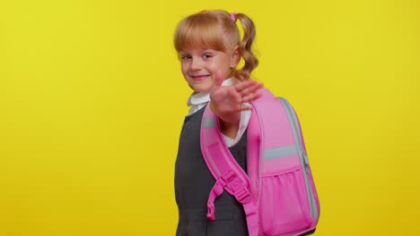 Cheerful-teenage-schoolgirl-kid-dressed-in-uniform-waves-hand-palm-in-hello-gesture-welcomes-someone