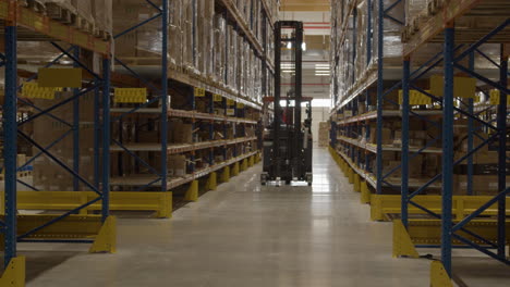 fork lift driving away through corridor in large shipping warehouse