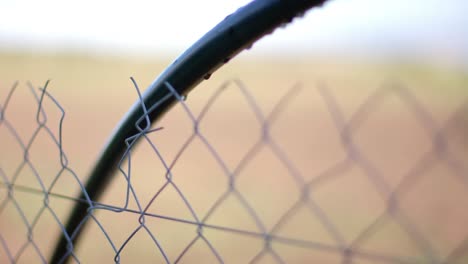 close up of fence with waterdrops on agricultural field at countryside on sunny day, slow motion