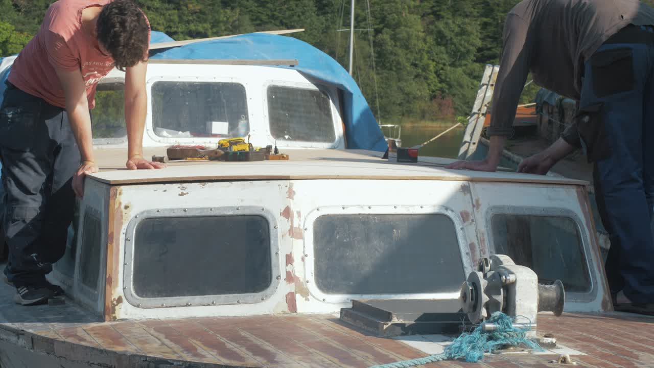 Apprentice working with an experienced carpenter repairs boat roof