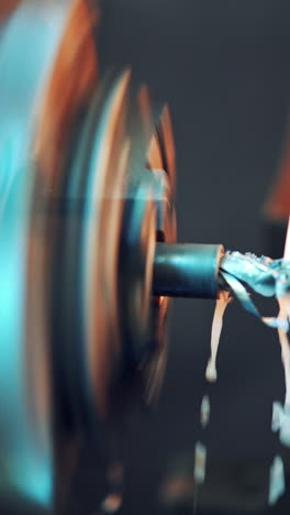 a lathe processes the metal workpiece with coolant which cool the tool and increase the productivity of the process. close-up. blurred background. vertical video