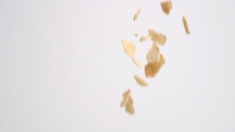 dehydrated dried apple pieces raining down on white backdrop in slow motion