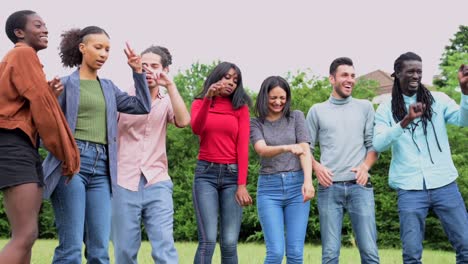 diverse group of friends having fun and dancing in a city park, outdoor party with people from different cultures, hanging out and relaxing outdoors in summer