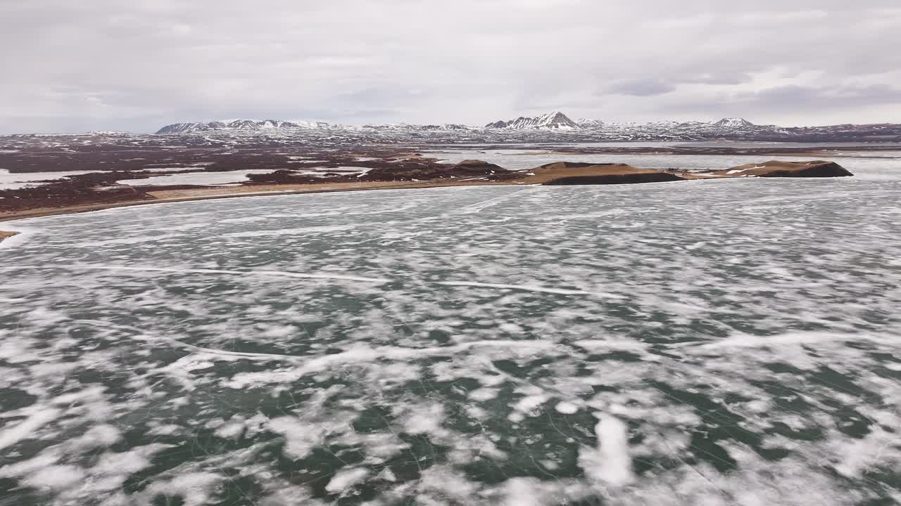 icy Lake Mývatn with snowy terrain and volcanic mountains near Skútustaðir village. Reykjahlíð, Iceland