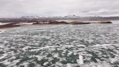 icy lake mývatn with snowy terrain and volcanic mountains near skútustaðir village. reykjahlíð, iceland