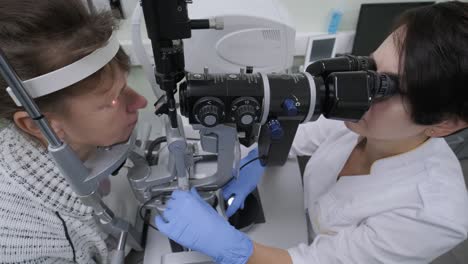 la mujer está viendo a través del oftalmoscopio en los ojos del paciente en la clínica oftalmológica. inspección profesional de la visión