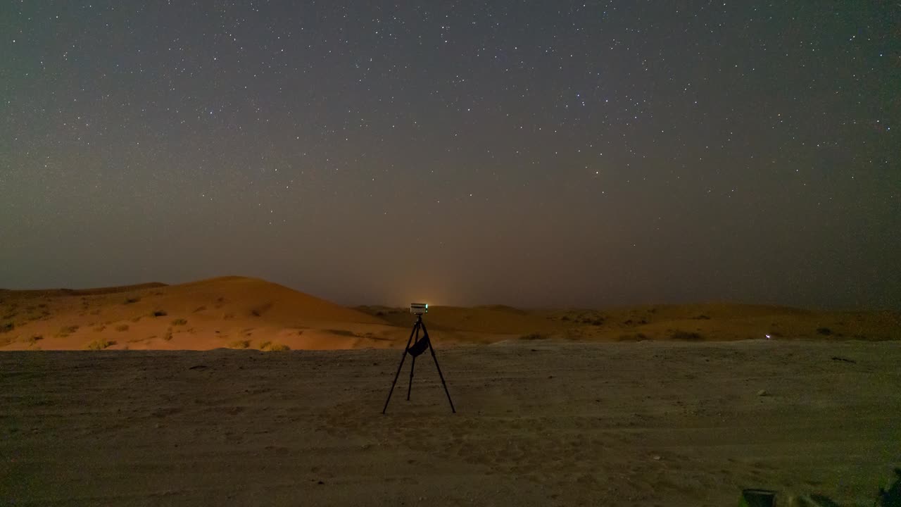 A star gazing party in the Al Qua'a Desert of Abu Dhabi landscape under a starlit sky, with people observing the rising Milky Way core with a smart telescope, star tracker, and cameras - time lapse
