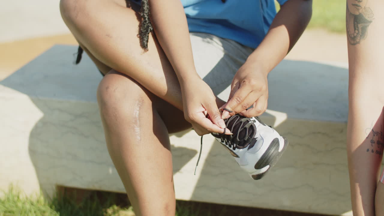 mujer sentada en un banco y atando cordones en zapatillas de deporte