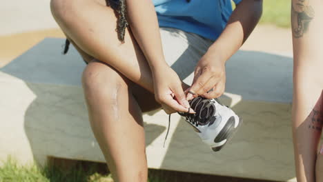 woman sitting on bench and tying laces on sneakers