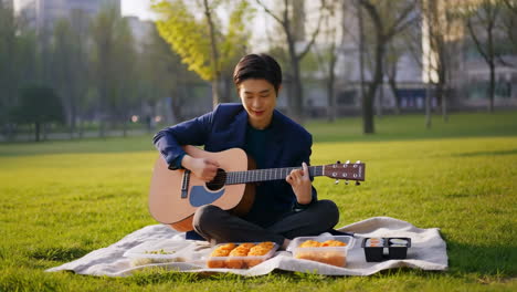 man playing guitar during a picnic in the park
