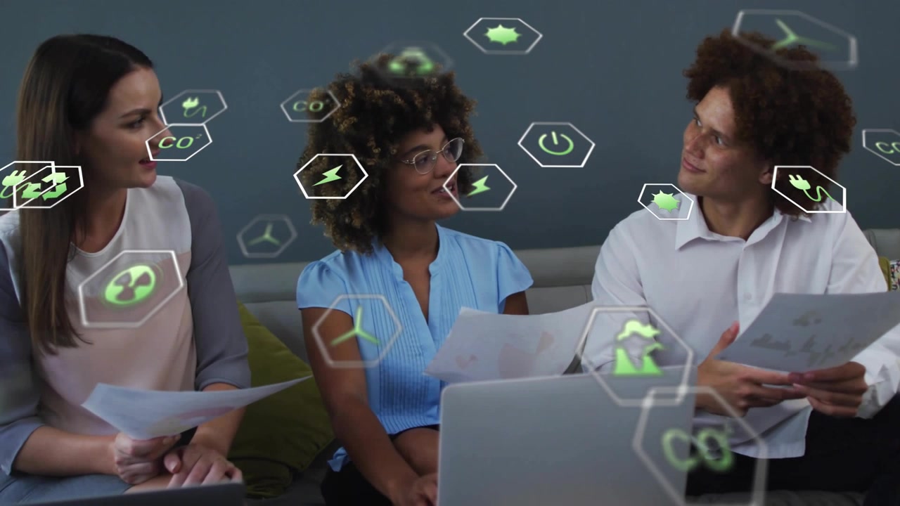 Relatore centrale che presenta un'attività toccando il laptop, con un team che legge documenti e sovrapposizione di icone verdi.